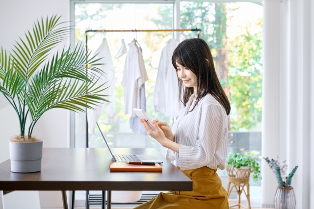 窓辺でパソコン作業をする女性